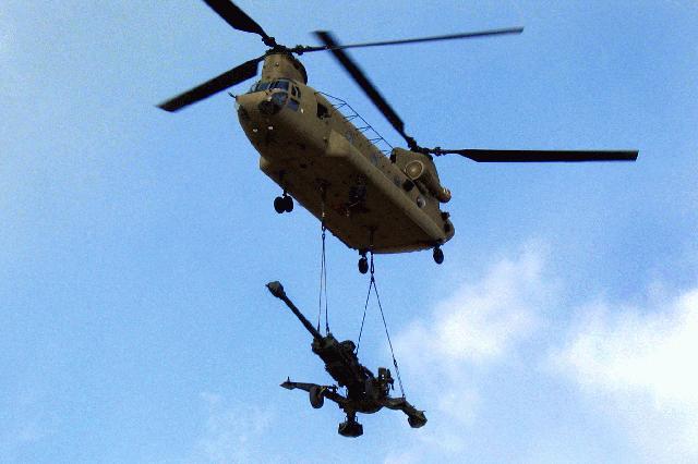 Trực thăng vận tải CH-47 Chinook đang tải một khẩu pháo 155 mm M-777 trên vùng trời Afghanistan.