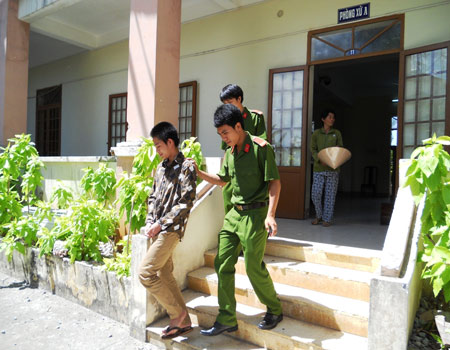 Nguyễn Ngọc Lĩnh bị áp giải ra xe sau phiên tòa, đằng sau là người mẹ của Lĩnh ngóng theo con.