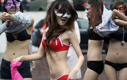 Còn 8 cô gái này, đeo mặt nạ mặc nội y nhảy nhót trên phố, gần nhà ga tàu điện ngầm ở Guangzhou (Quảng Đông, Trung Quốc) với tấm bìa cứng cùng khẩu hiệu: 