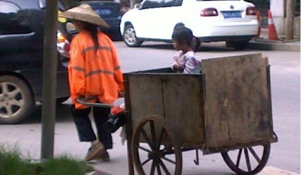 Hình ảnh một nữ công nhân vệ sinh đi thu dọn rác và mang theo cô con gái khoảng 4 đến 5 tuổi trong thùng xe rác