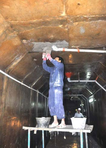 Công nhân trát xi măng chống thấm trên trần của đường hầm công trình thủy điện.