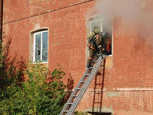 Một người lính chữa cháy đang leo thang qua cửa sổ xưởng may 