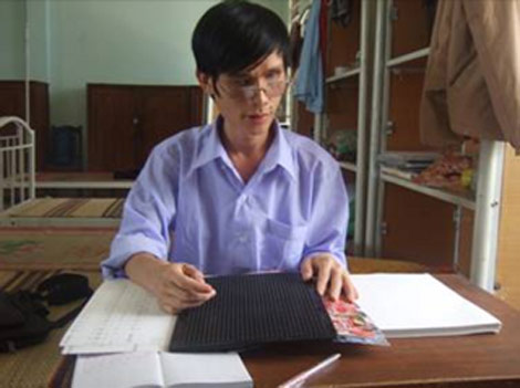 Nguyễn Văn Tý bên chiếc bàn viết bằng chữ nổi đã giữ gần 20 năm qua.