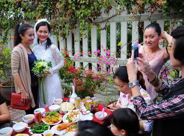 Hải Yến mặc áo dài cưới bằng ren trắng, khoe vẻ đẹp dịu dàng, đằm thắm. Cô tươi cười tiếp khách với mâm cỗ giản dị, trái ngược với tiệc cưới 