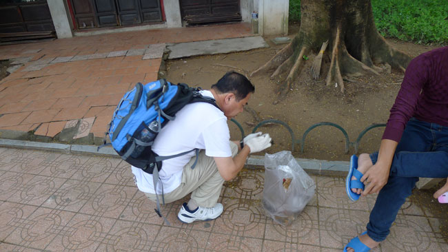 Một thanh niên thờ ơ khi thấy ông Ninomiya ngồi xổm dưới đất, dùng tay hớt đống rác ở bên cạnh