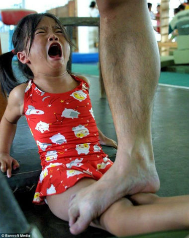 Hình ảnh một bé gái đau đớn khi HLV thể dục huấn luyện cho cô bé bằng biện pháp hà khắc