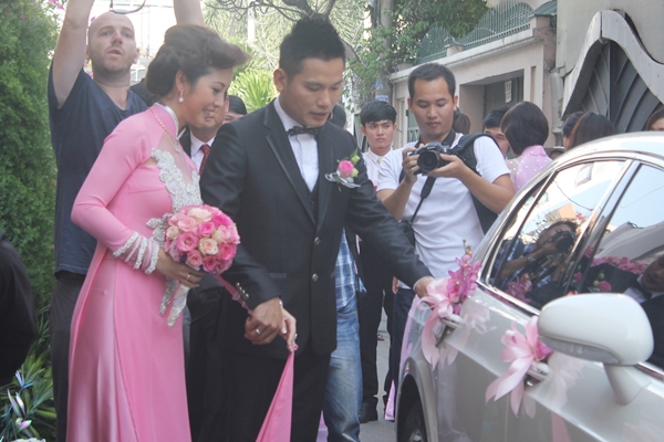   Trong bộ áo dài hồng rực rỡ, Jennifer Phạm khoác tay chú rể Đức Hải cười hạnh phúc nhanh chóng bước lên xe ôtô.