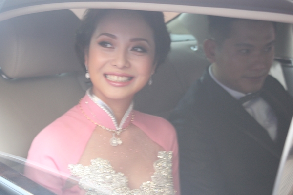 Vào bên trong xe, Jennifer nhìn ra ngoài nở nụ cười tươi chào mọi người để về nhà chồng.