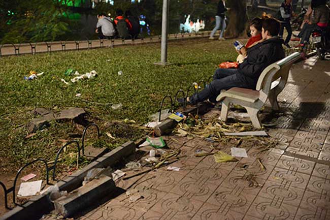 Người ngồi lên rác thải, ngay cả hàng gạch bao quanh vườn cỏ cũng bị hư hỏng