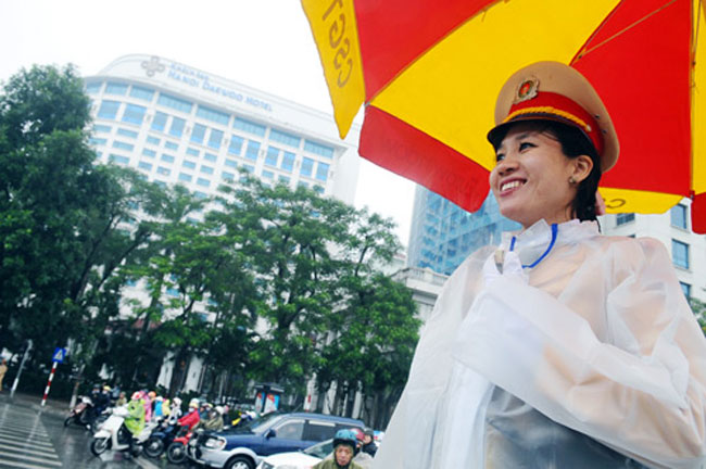 Mặc áo mưa đứng hướng dẫn giao thông tại ngã tư Kim Mã - Liễu Giai, thiếu uý Nguyễn Mai Huyền (Đội CSGT số 2) vẫn vui vẻ hướng dẫn giao   thong cho mọi người.