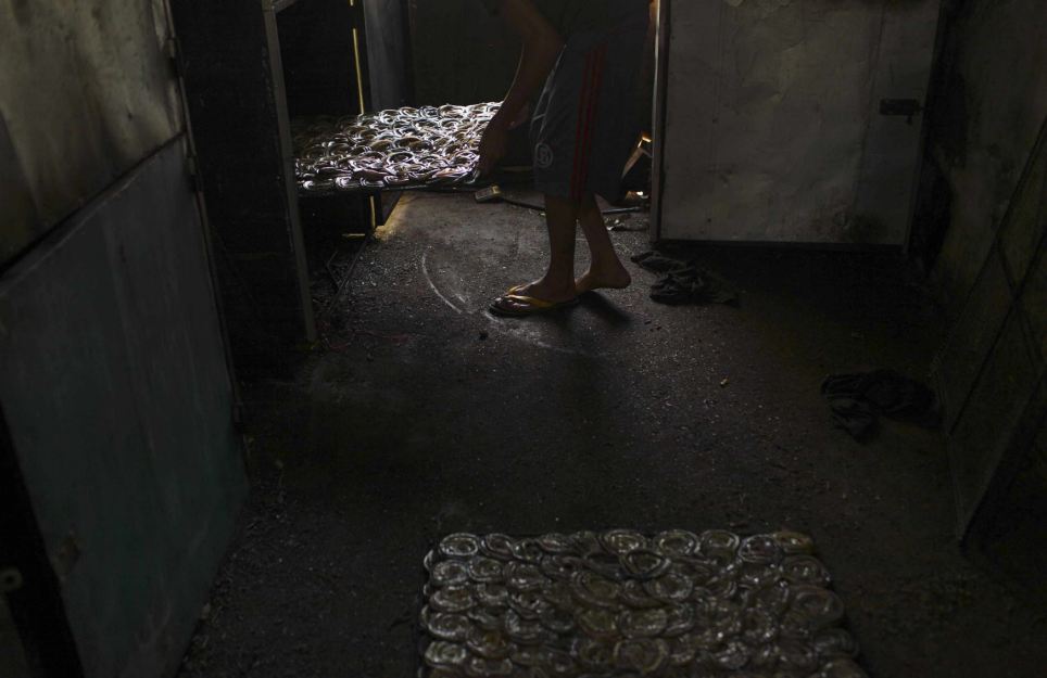  Một công nhân đặt các phên đựng đầy da rắn vào bên trong lò sấy.