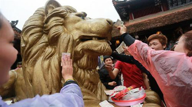 Trong khi đó, tại chùa Hương, khách thập phương tứ xứ đổ về thi nhau bôi tiền, để tiền vào miệng sư tử đá cầu may trước sân Thiên Trù cầu lộc, cầu may