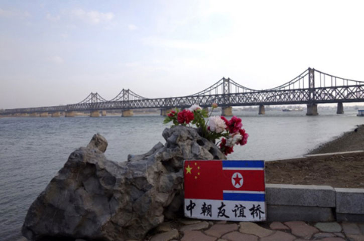 Tấm biển in hình cờ Trung Quốc và Triều Tiên đặt bên bờ sông Áp Lục, thành phố Đan Đông, Trung Quốc, gần cầu hữu nghị Trung-Triều, nối liền hai nước. Dòng chữ này ghi tên cây cầu: Hữu nghị Trung - Triều.