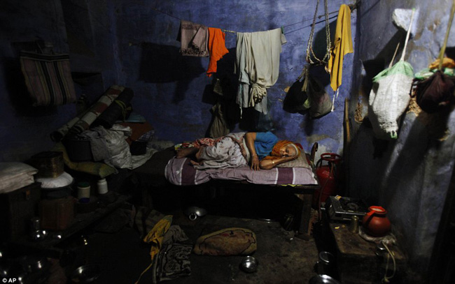 Một góa phụ cao tuổi nằm ngủ trên chiếc giường trong ngôi nhà chật hẹp và bừa bộn của mình ở Varanasi.