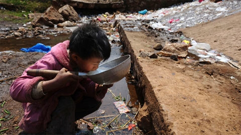 Một đứa trẻ uống nước gần một con suối ở Phúc Nguyên. (Ảnh: Reuters)