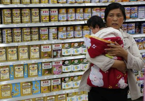 Một bà mẹ bế con nhỏ đi mua sữa trong một siêu thị ở thủ đô Bắc Kinh, Trung Quốc - Ảnh: Reuters