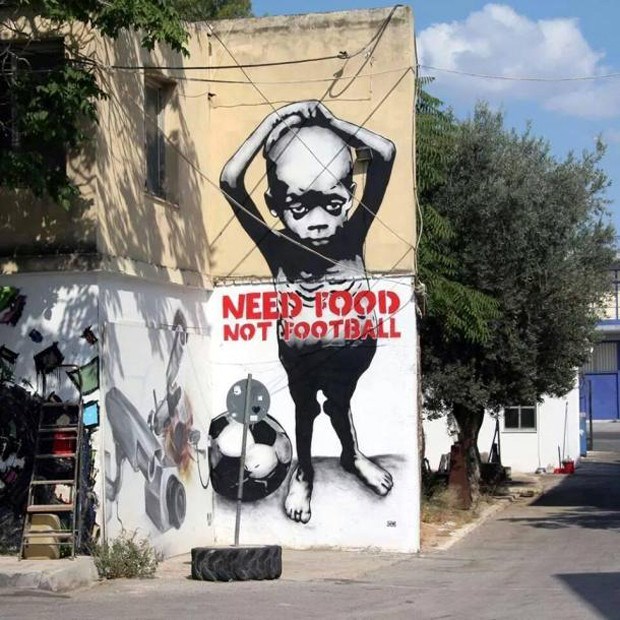 Bức graffiti "Cần thức ăn, không cần bóng đá" trên một bức tường ngoài phố