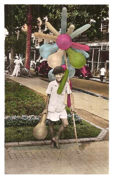 Một cậu bé bán bóng bay dạo trên phố Sài Gòn cười tươi, "tạo dáng" trước ống kính.