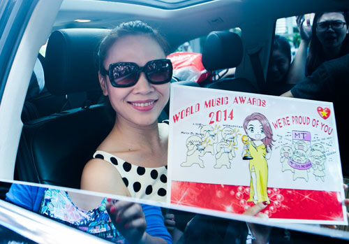 Nữ ca sỹ hạnh phúc khoe bức tranh người hâm mộ vẽ tặng với chiếc váy vàng cô đã mặc khi nhận giải thưởng World Music Awards 2014.