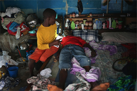 Một cậu bé chăm sóc cha mình trước khi họ được đưa đến khu cách ly dịch bệnh Ebola ở Liberia.