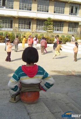 Qian ngồi xem các những trẻ em khác vui chơi vào tháng 2/2005.