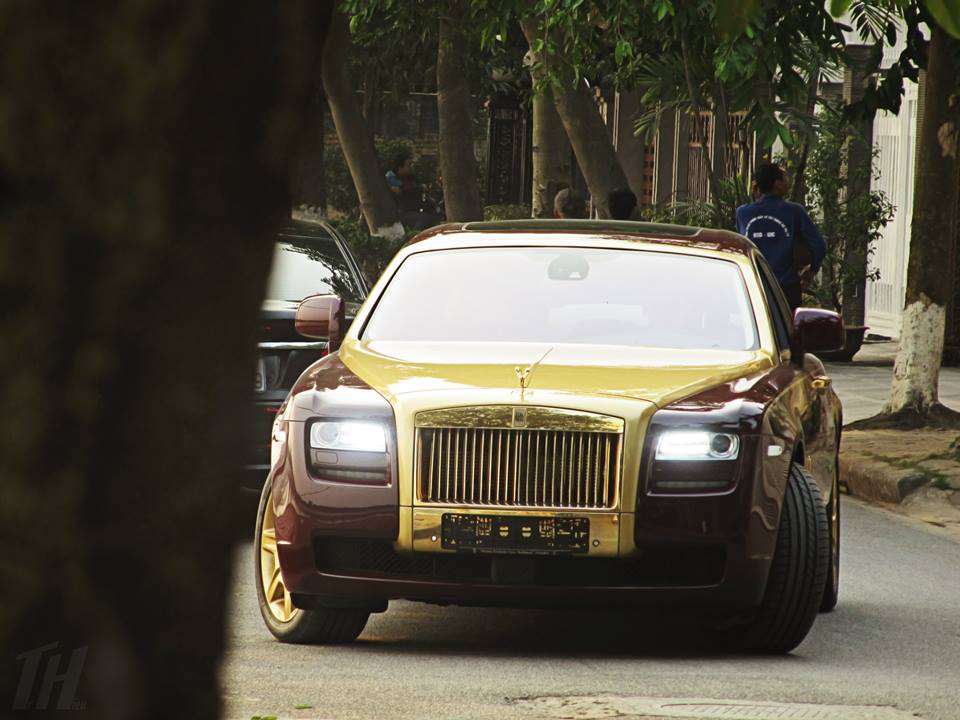 Chiếc Rolls-Royce Ghost này có nước sơn màu đỏ mận và lớp áo dát màu vàng chạy từ mép trần kính chắn gió, qua ca-pô xuống hết mặt tản nhiệt đồ sộ đặc trưng nhà Rolls-Royce.