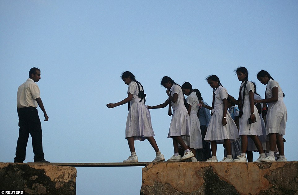 Một nhóm nữ sinh đi qua tấm ván nhỏ trên tường của pháo đài cổ Galle để tới trường ở Sri Lanka.