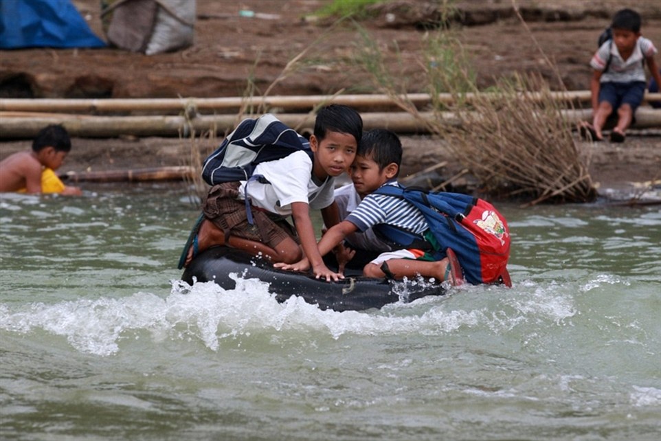 Hai học sinh nhỏ phải dùng xăm ô tôi để làm bè vượt sông tới trường tại tỉnh Rizal, Philippines.