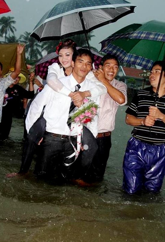 Chú rể bì bõm lội nước cõng cô dâu đi qua cánh đồng ngập trắng nước trong đám cưới của mình tại Hương Sơn, Hà Tĩnh.