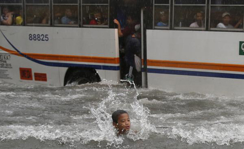 Một cậu bé đang bơi trên tuyến phố bị ngập lụt