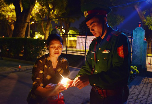 Nữ cựu chiến binh Nguyễn Thị Hòa (58 tuổi, nhà ở quận Cầu Giấy) nhờ anh cảnh vệ châm nến và vái vọng từ phía ngoài.