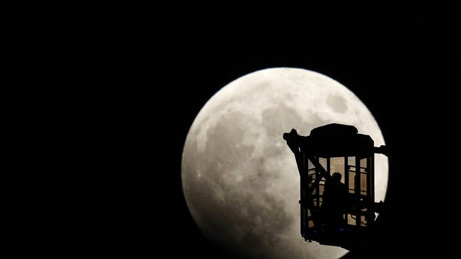 Một người đàn ông và một phụ nữ trên vòng quay Ferris tại thành phố Tokyo, Nhật Bản ngắm trăng khi nguyệt thực toàn phần bắt đầu vào tối 8/10.