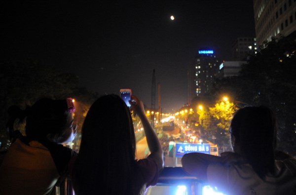 Một nhóm các bạn trẻ đón xem và chụp hình hiện tượng trăng máu ở cầu vượt trên đường Xuân Thủy.