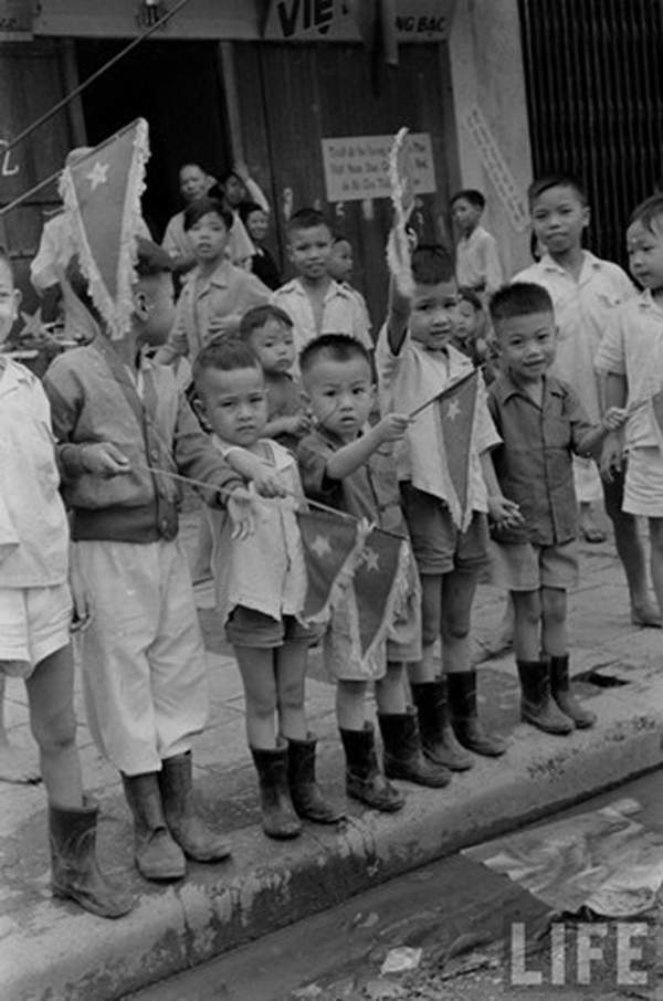 Trẻ em trên phố Hàng Bạc cầm cờ vẫy chào bộ đội Việt Minh.