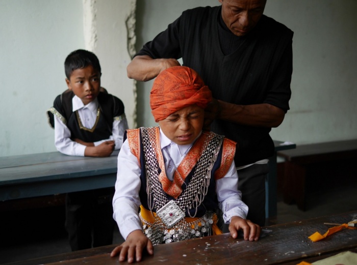 Cậu bé dân tộc Khasi được ông nội hướng dấn đeo khăn truyền thống trước khi tham dự một lễ hội trong làng.