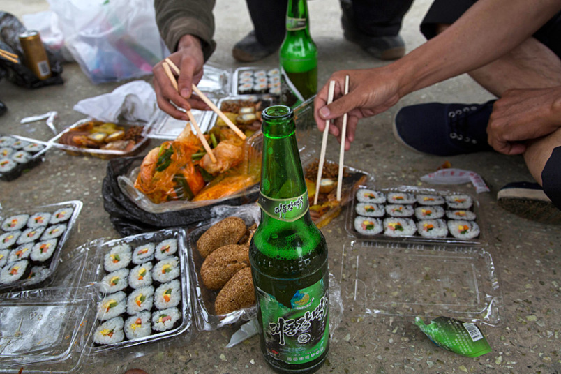 Những người đàn ông ăn trưa với món ăn truyền thống của Triều Tiên và bia Taedonggang ngay trên lề đường ở tỉnh Bắc Hwanghae.