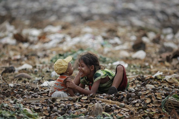 Một bé gái đang chơi đùa cùng em trai ở sân rác vùng ngoại ô Yangon, Myanmar.