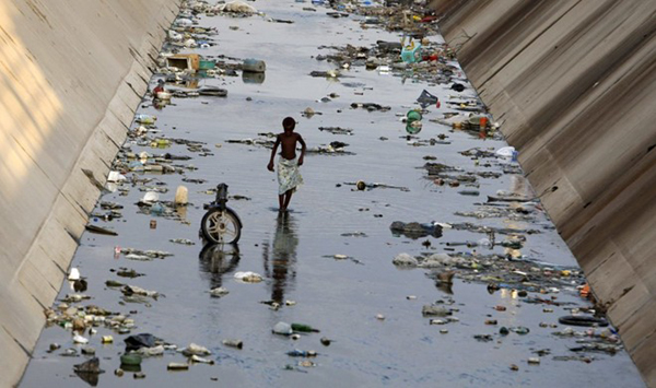 Cậu bé đi bộ qua một kênh đào ô nhiễm ở Benguela, Angola.