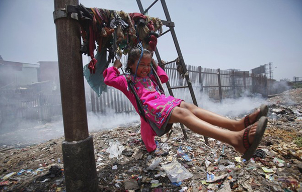 Một bé gái với nụ cười hạnh phúc đang chơi đu quay ở khu tập trung rác ở Mumbai, Ấn Độ.