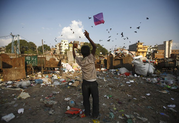 Hình ảnh một bé trai thả diều gần dòng sông Bishnumati, Kathmandu, Nepal với đàn quạ đen đang bay trên những đống rác thải.