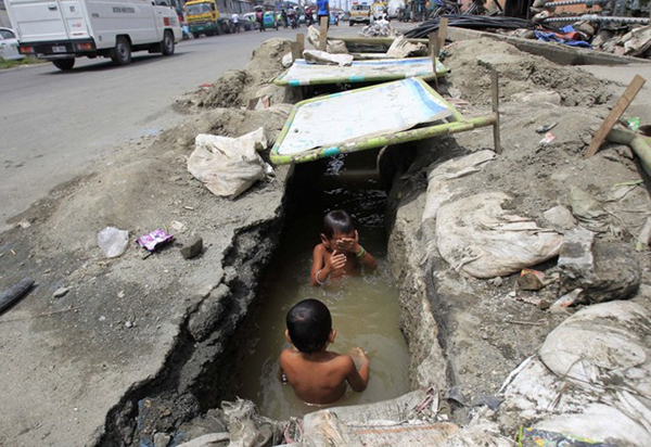Những đứa bé này đang tắm ở một hệ thống thoát nước lộ thiên tại thành phố Manila, Philippines.