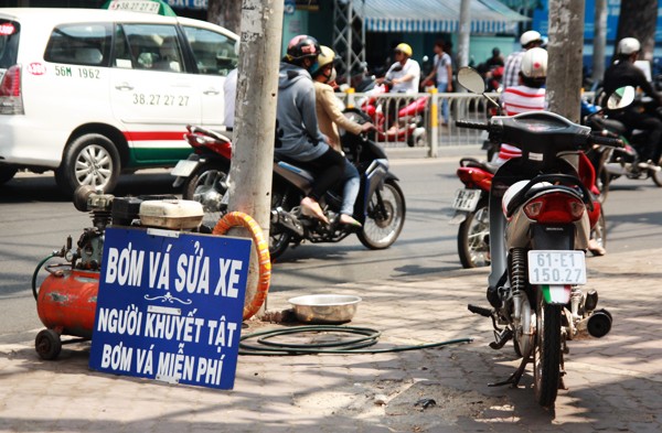 Suốt 2 năm qua, trên một góc đường khác ở Sài Gòn, ngay ngã tư Nguyễn Thị Minh Khai giao Cống Quỳnh, Quận 1, một tấm biển đặc biệt đã được dựng lên: Bơm vá xe miễn phí cho người khuyết tật.