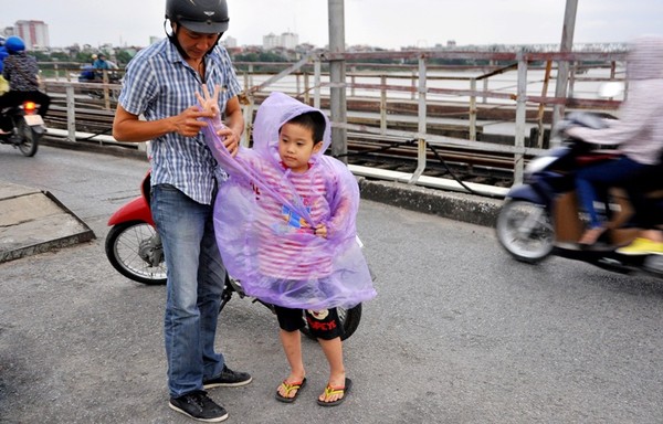 Bố mặc thêm áo mưa cho con để đỡ lạnh khi di chuyển qua cầu Long Biên.