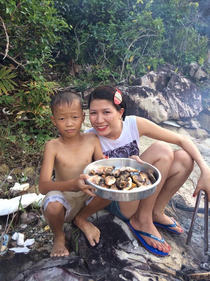 Trang Trần cưới tươi tắn bên em bé bán cá thu vùng biển.