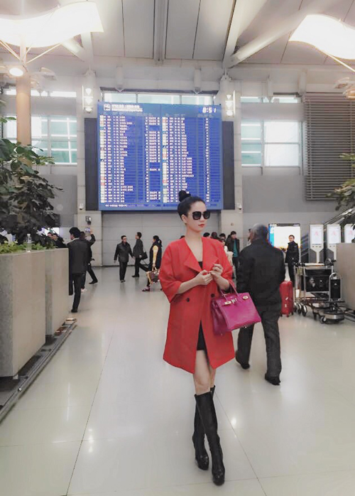 Cũng váy da ngắn Ngọc Trinh kết hợp với áo khoác màu đỏ, nổi bật tại sân bay.