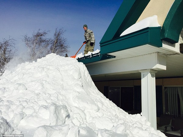 Người dân thu dọn tuyết trên mái nhà.