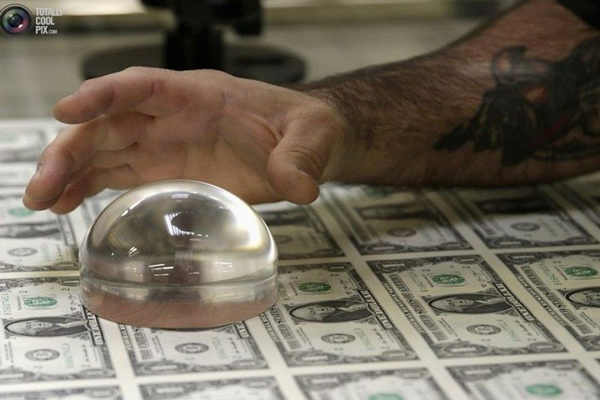 Nhân viên đang kiểm tra tờ tiền bằng kính lúp.