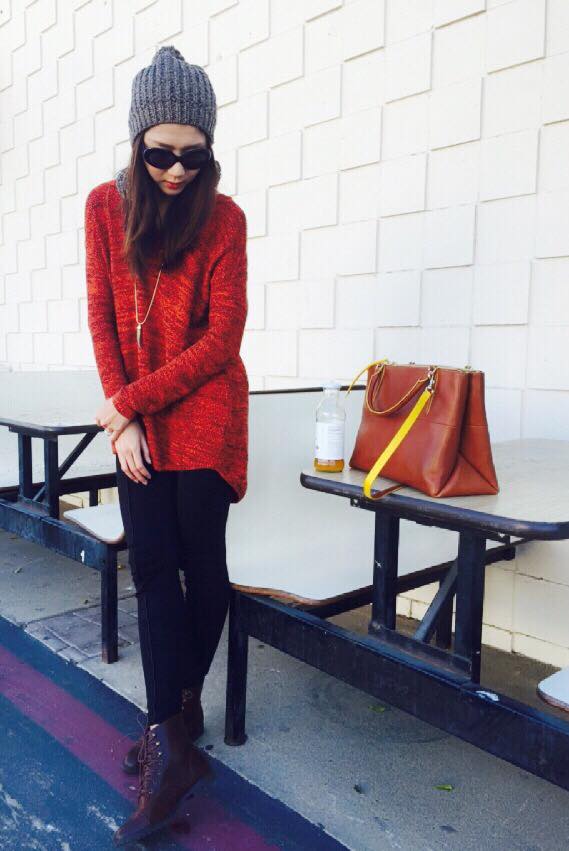 Siêu mẫu cá tính với áo len rộng màu đỏ với quần bó đen, giày boots cổ thấp.