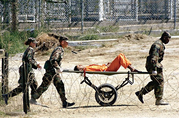 Sĩ quan quân đội chở một tù nhân tới phòng thẩm vấn trong trại X-Ray tháng 2/2002.