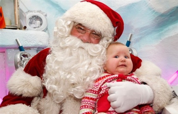 Trông em bé này không hề thích thú khi được ông già Noel ẵm.